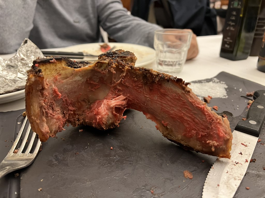 Partially eaten bistecca alla fiorentina at Trattoria Il Latini, showing the rare red interior on the bone