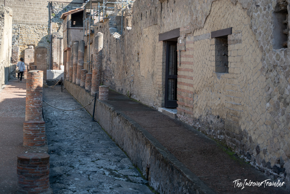 Ancient Roman street at Herculaneum, with brick columns, raised sidewalk, and opus reticulatum walls