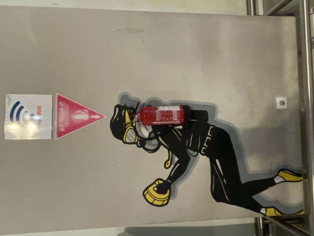 Street art of a scuba diver holding a fire extinguisher as a tank, Raja Ampat travel humor