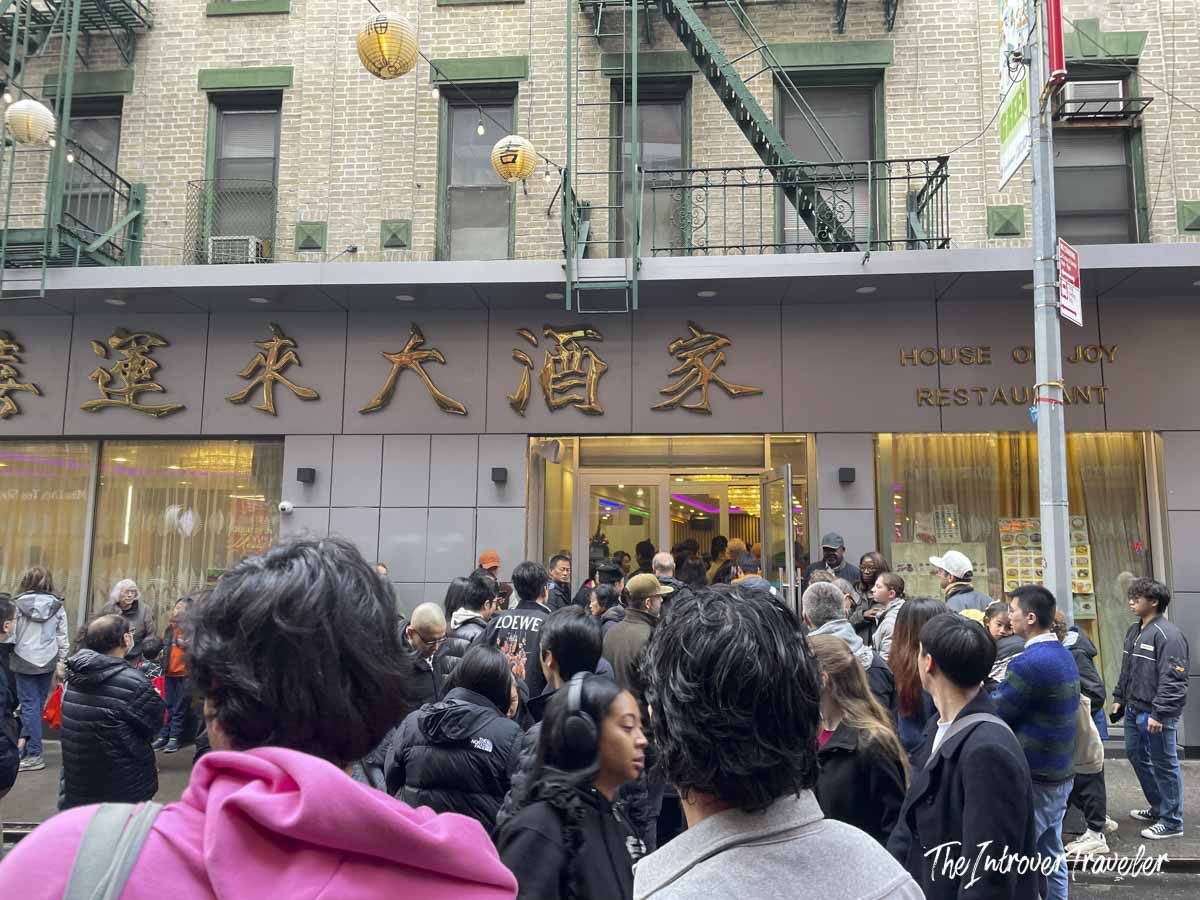 Crowd waiting outside House of Joy Restaurant in Manhattan Chinatown, with gold Chinese characters on the facade