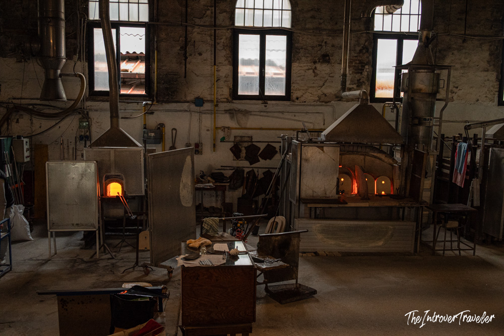 Interior of a traditional Murano glassblowing furnace with glowing kilns and tools on the workshop floor