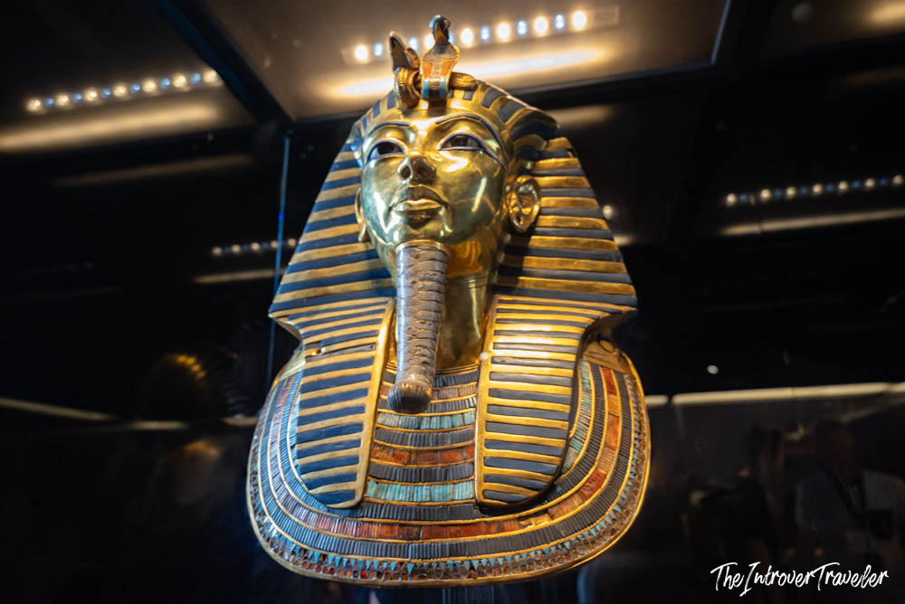 Gold death mask of Tutankhamun displayed under dramatic lighting at the Egyptian Museum Cairo