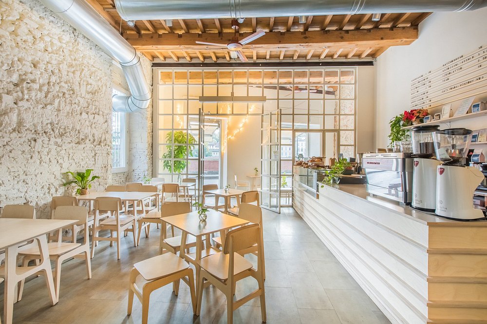 Bright minimalist interior of Melaleuca Bistrot, Florence, with exposed wood beams and espresso bar