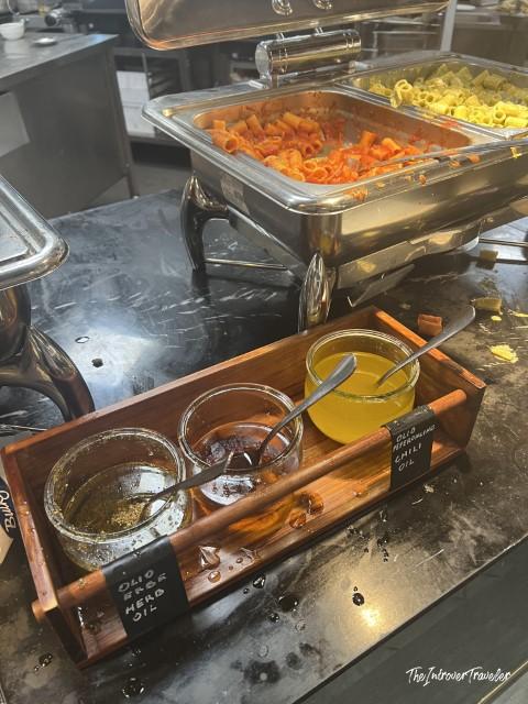 Pasta buffet station at Plaza Premium Lounge FCO, with herb oil and chili oil condiments