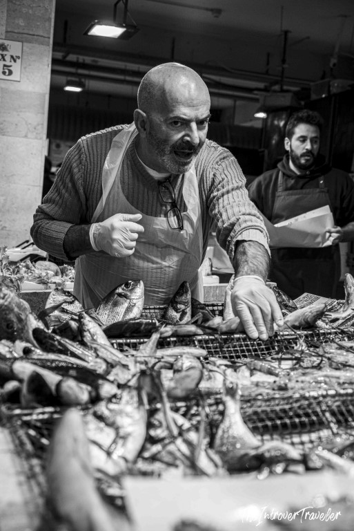 Fishmonger arranging fresh catch at a bustling coastal city fish market stall