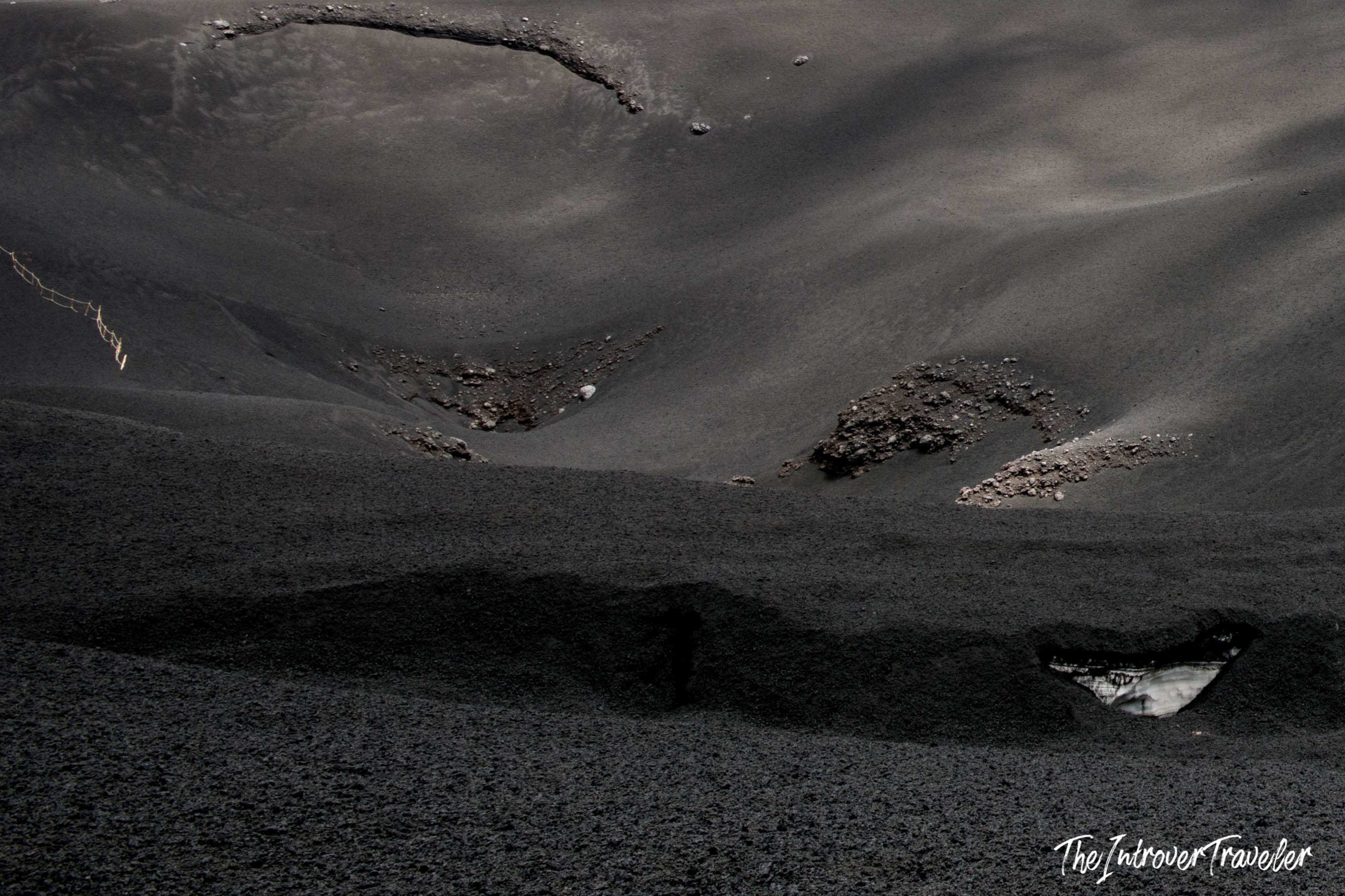 Black volcanic ash and lava rock terrain on Mount Etna, Sicily, during a hiking excursion