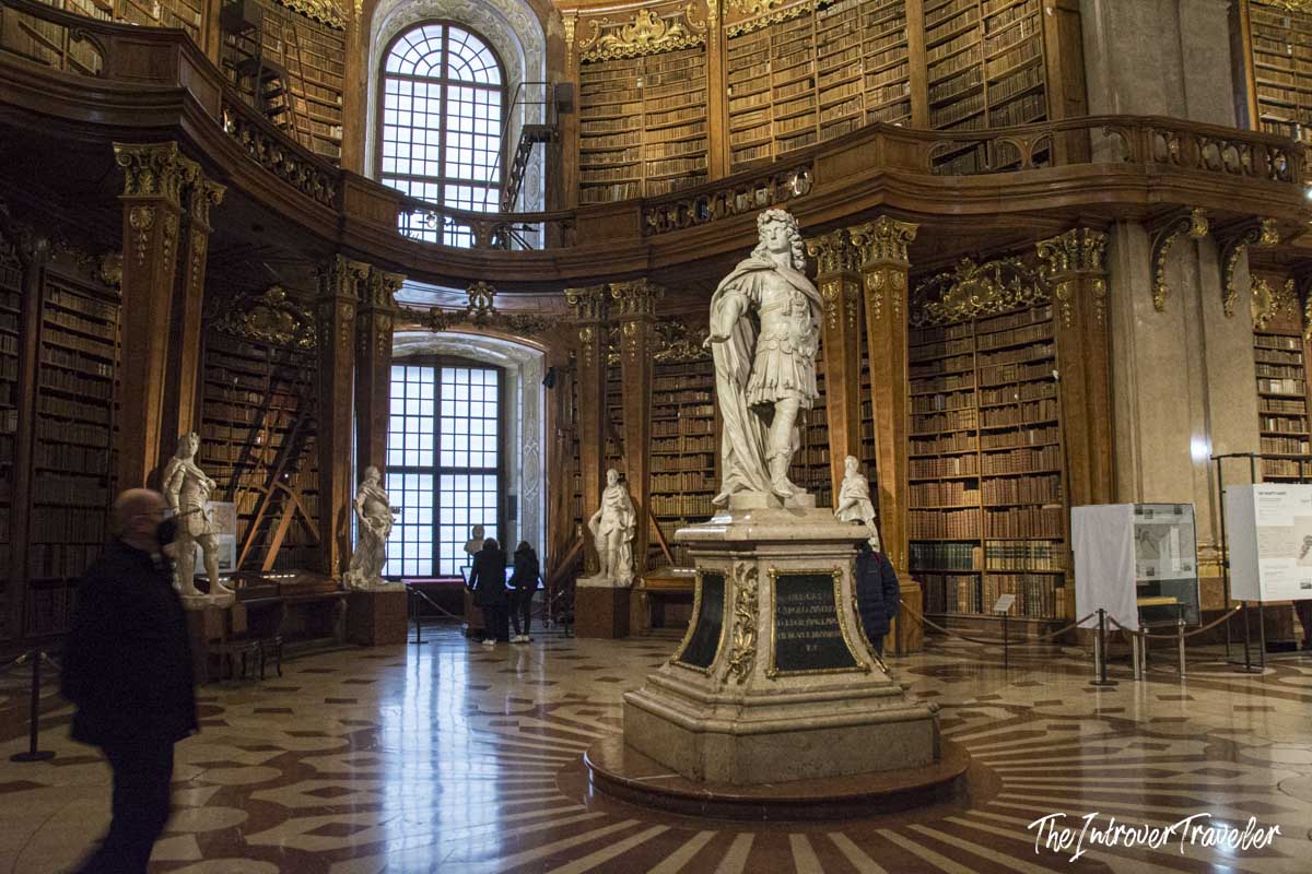 Austrian National Library State Hall in Vienna, with the central Charles VI statue amid floor-to-ceiling baroque bookshelves