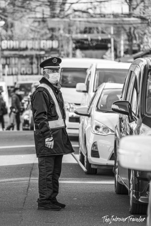 Japanese traffic officer in uniform and face mask directing vehicles near Tsukiji fish market, Tokyo