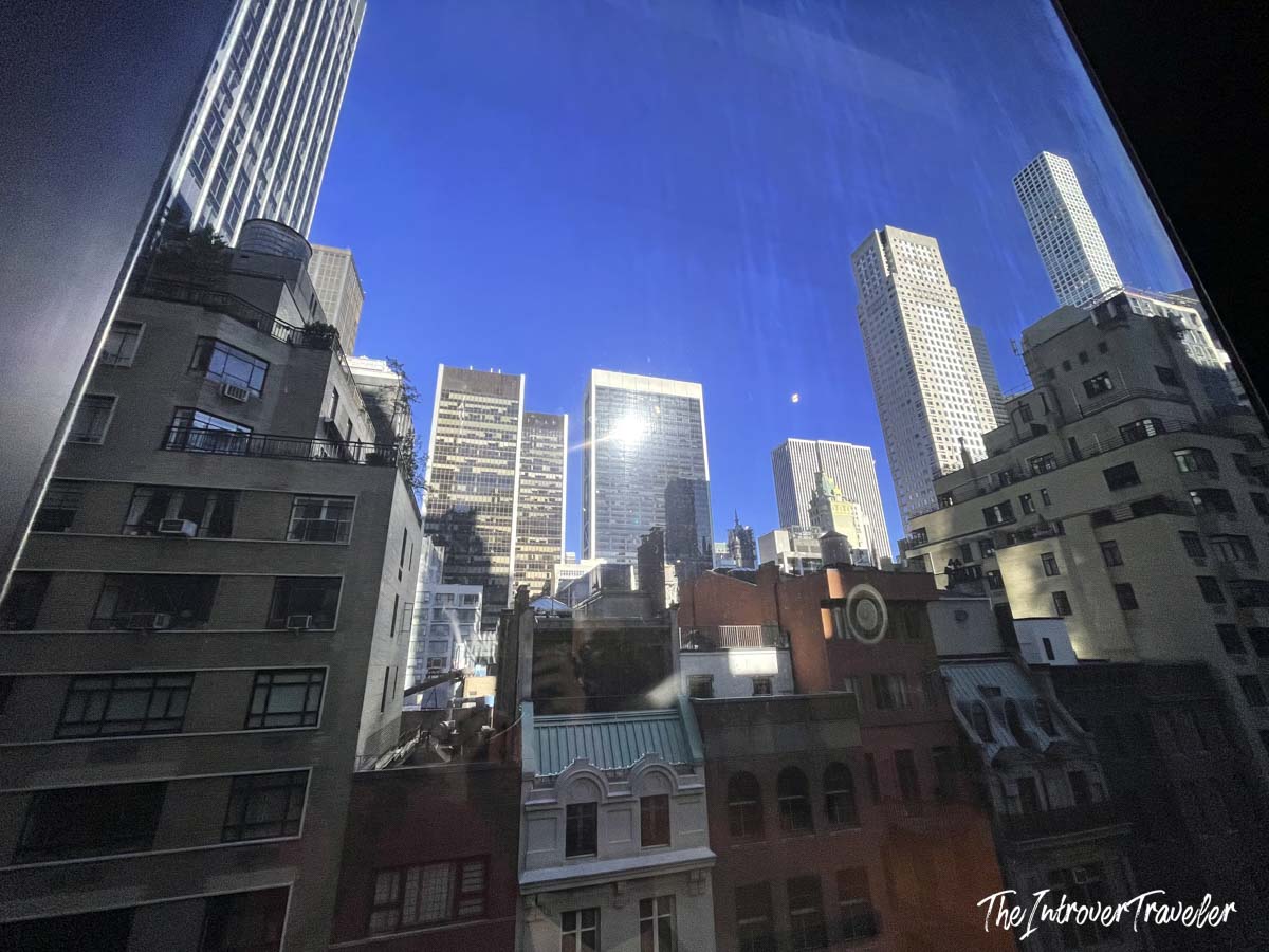 View of Midtown Manhattan skyscrapers through a MoMA window, between 5th and 6th Avenue New York