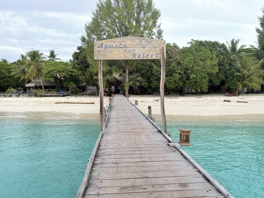 Wooden jetty leading to Agusta Eco Resort on a white sand beach in Raja Ampat, Indonesia