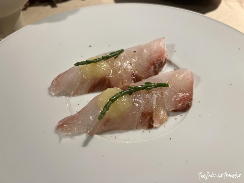 Raw fish crudo appetizer with green herb garnish, served at Trattoria Da Lucio in Rimini
