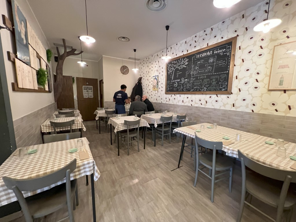 Yuzuya dining room in Bologna, with checkered tablecloths and a teishoku lunch chalkboard menu