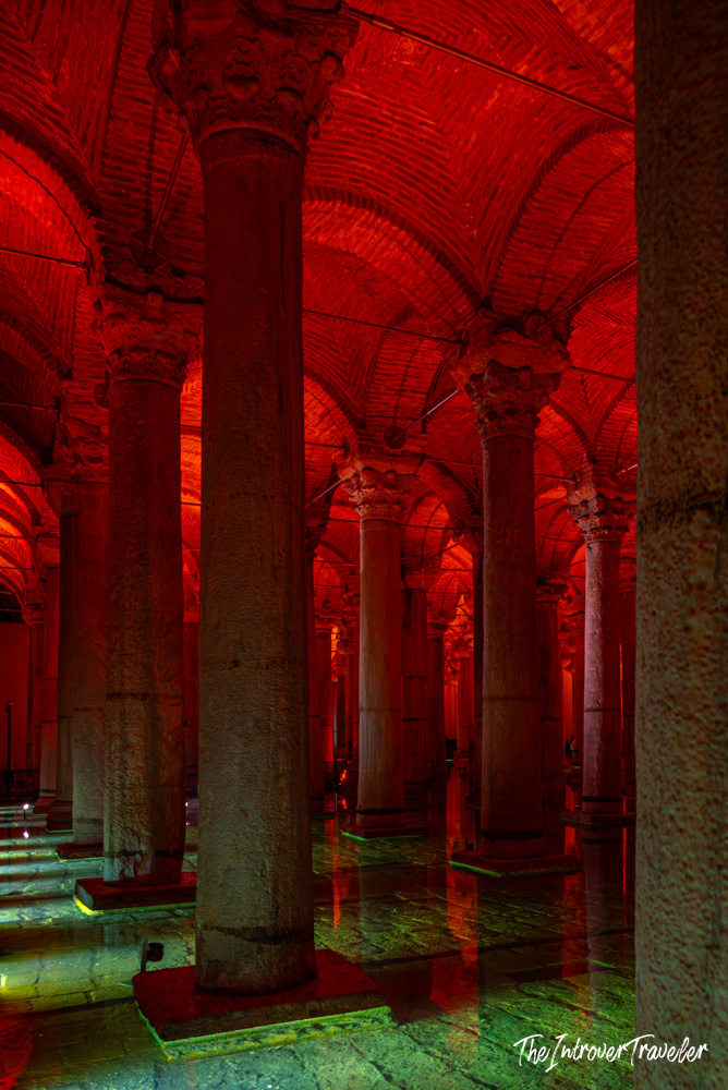 Red-lit interior of the Basilica Cistern in Istanbul, showing rows of ancient marble columns