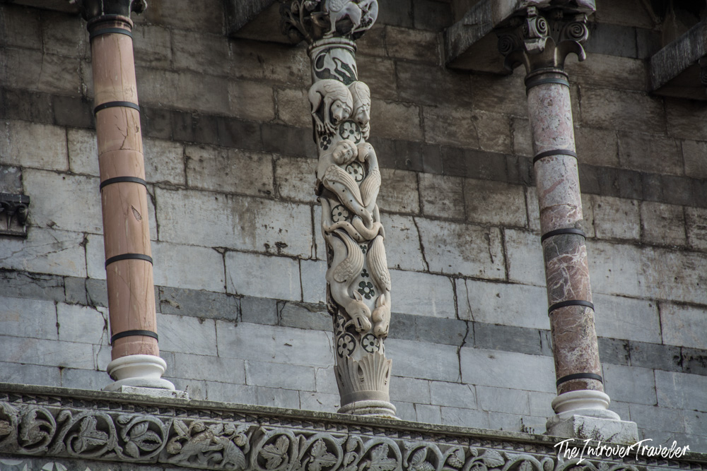 Ornate carved marble column with figures on the facade of Lucca Cathedral, Tuscany