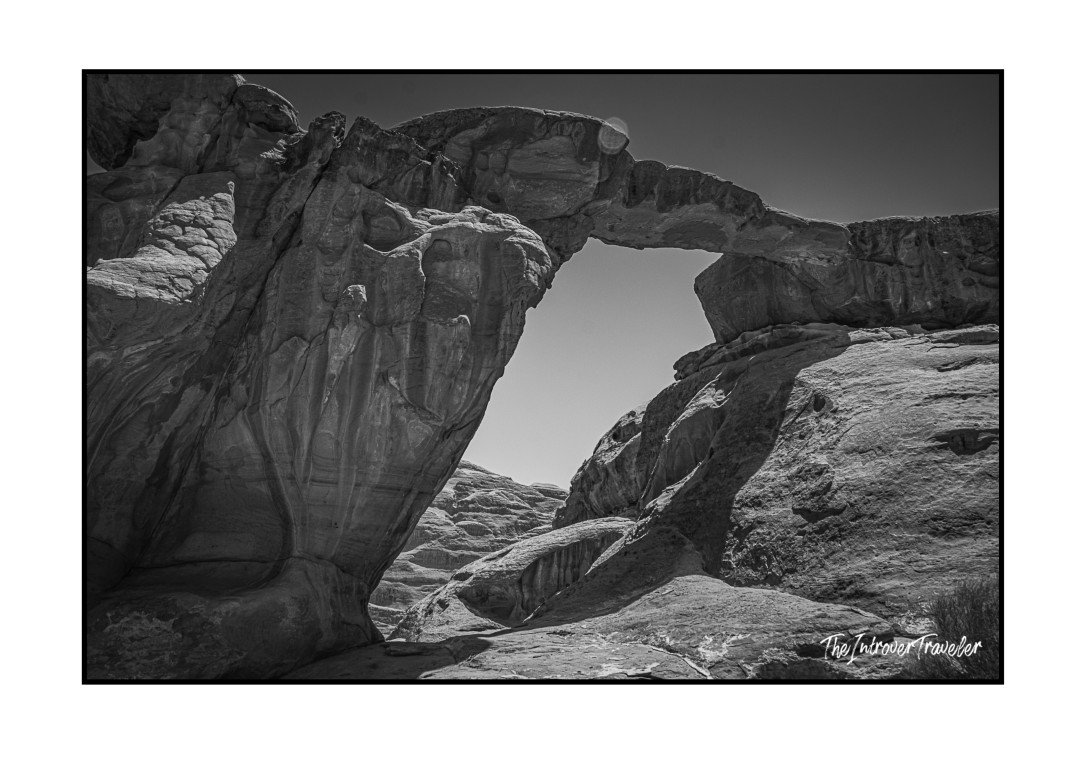 Black and white shot of a natural sandstone arch in Wadi Rum desert, Jordan