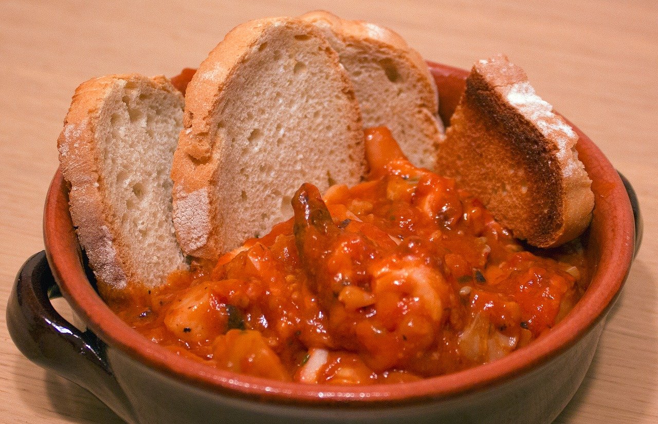 Tuscan shrimp in spicy tomato sauce served in a terracotta bowl with crusty bread slices