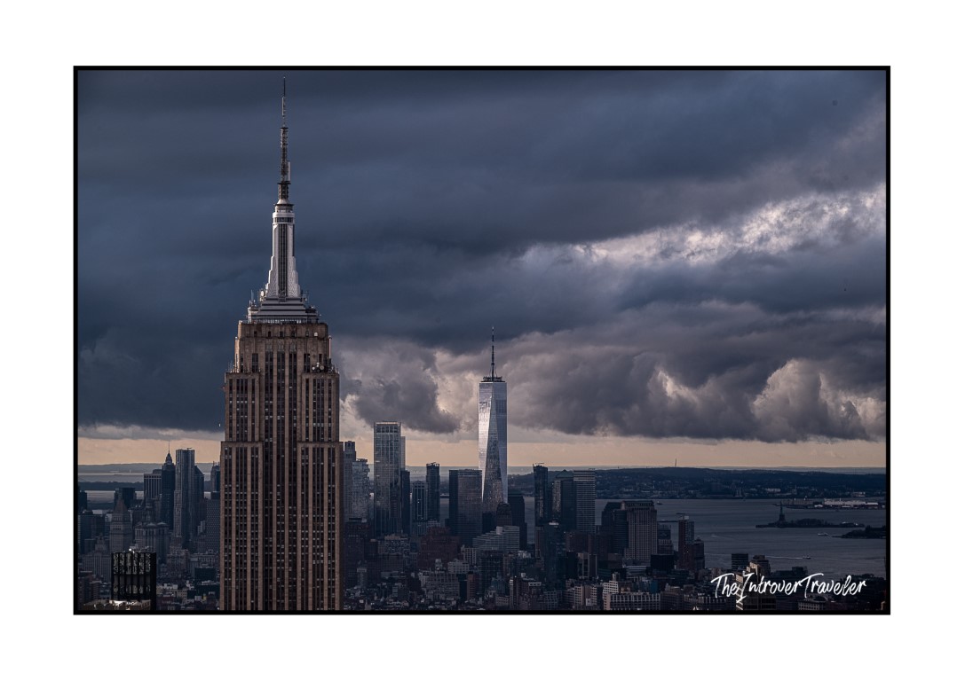 Empire State Building and One World Trade Center dominating the NYC skyline under dramatic storm clouds