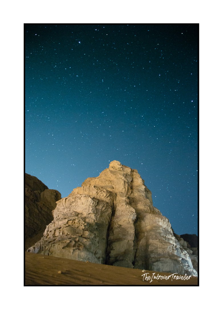 Starry night sky over a sandstone rock formation in Wadi Rum desert, Jordan