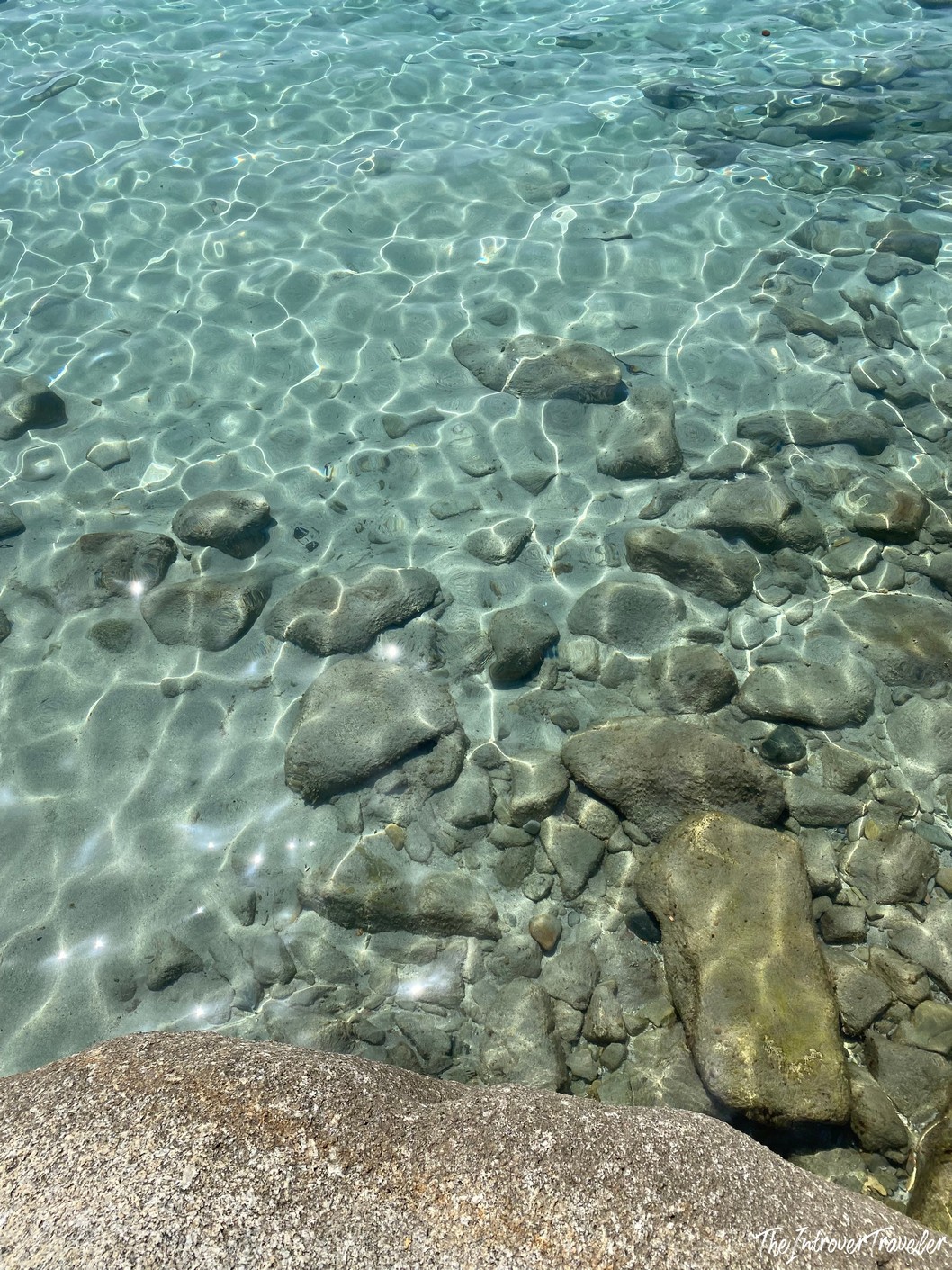 Crystal-clear shallow water over smooth rocks at a south Sardinia pebble beach