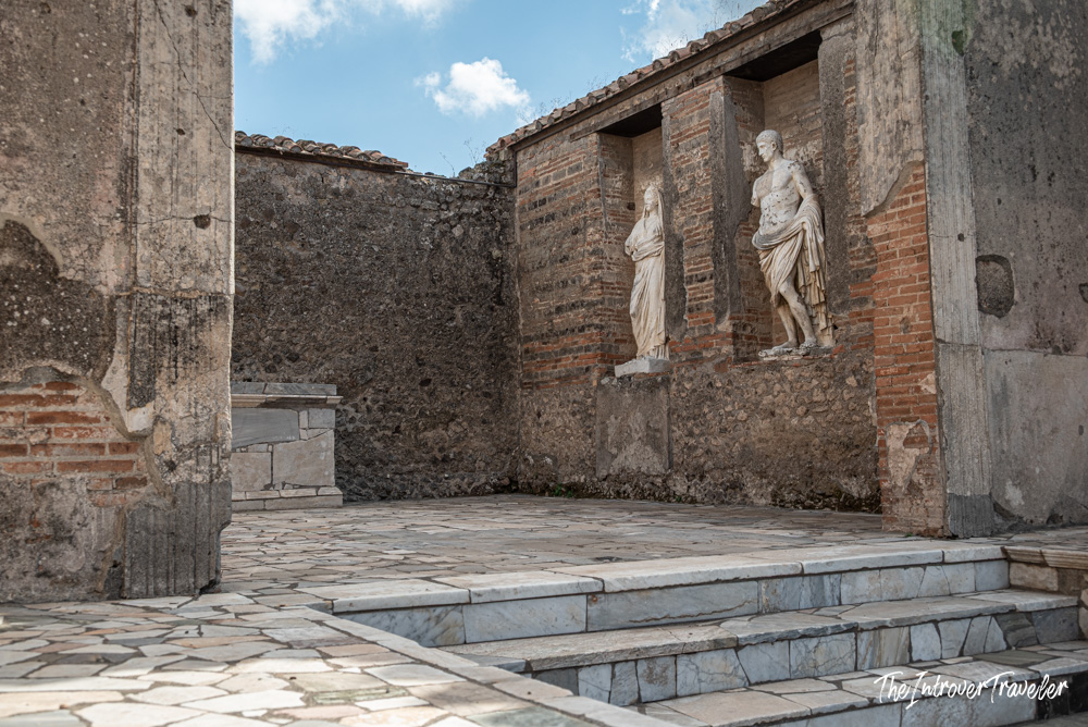 Two ancient Roman statues in a brick niche at the ruins of Pompeii, Italy
