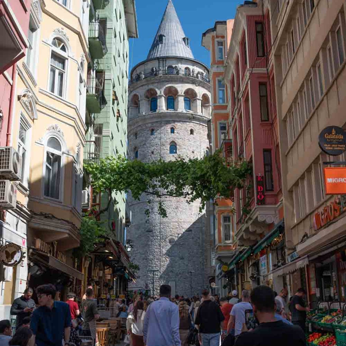 Galata Tower rising above a busy pedestrian street in Istanbul's Beyoglu neighborhood