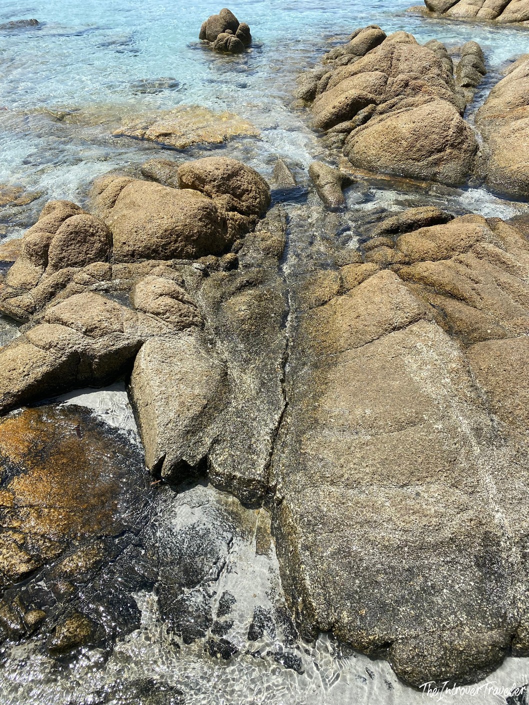 Granite boulders lapped by crystal clear turquoise water on a south Sardinia beach shoreline