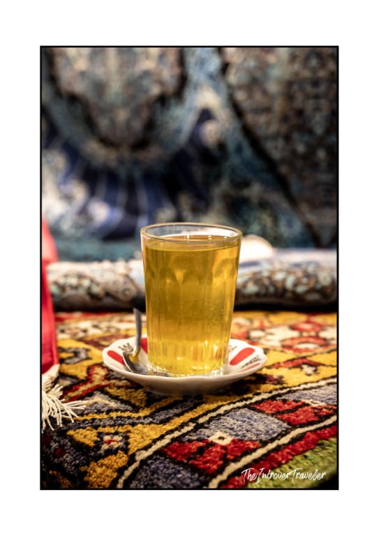 Glass of Turkish tea served on a decorative saucer atop colorful carpets in Istanbul