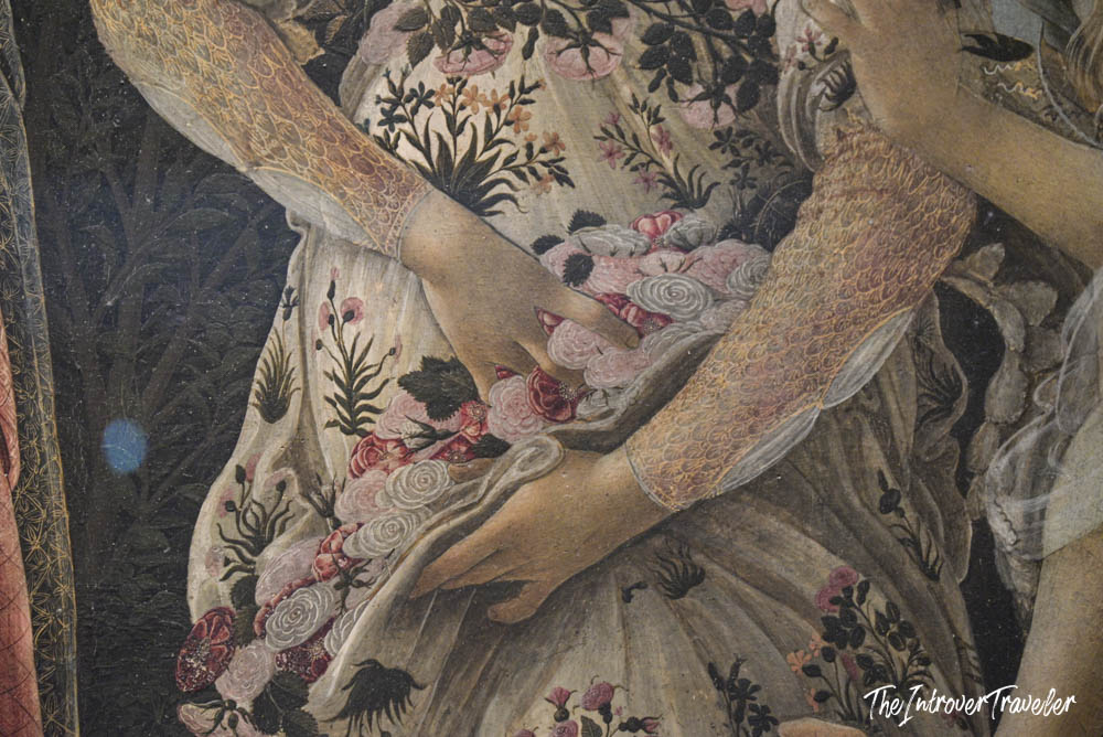 Close-up detail of Botticelli's Primavera, showing floral dress and hands, at the Uffizi Gallery Florence