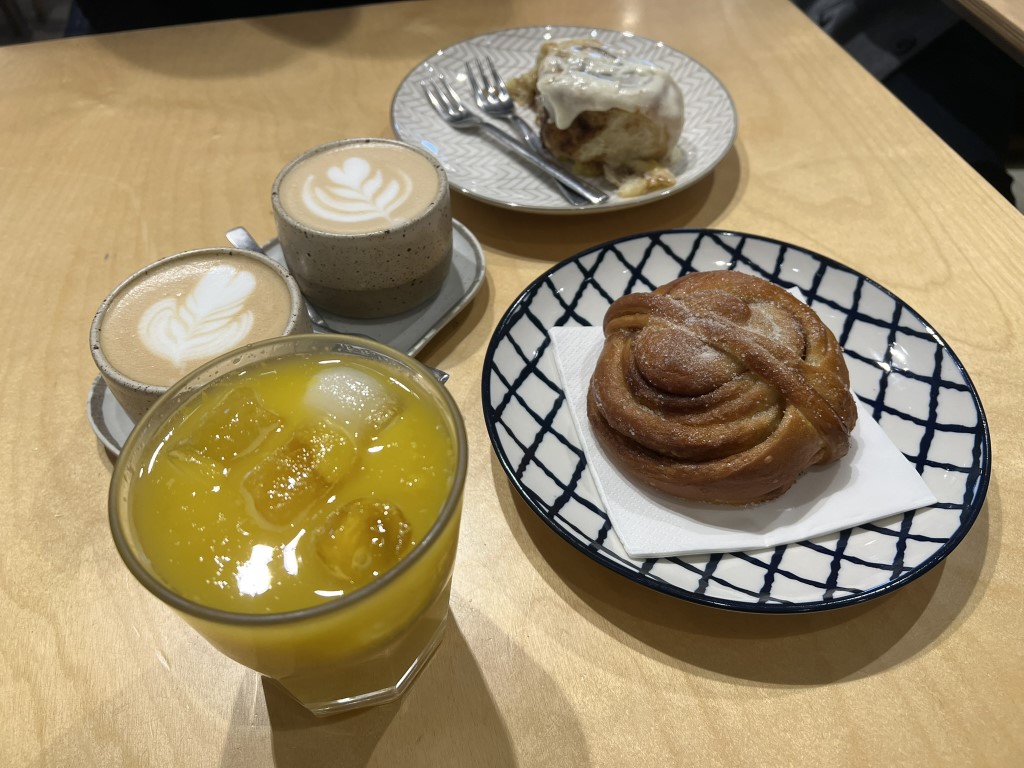 Melaleuca Bistrot breakfast spread: lattes, orange juice, cinnamon roll, and cardamom bun in Florence