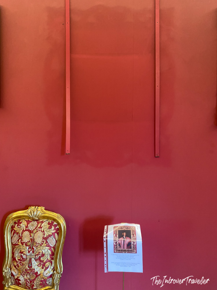 Gilded baroque chair and Pontormo portrait label on a vivid red wall in Lucca, Tuscany
