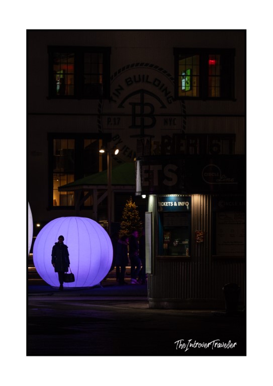 Silhouette of a pedestrian against a glowing purple orb near the Tin Building, NYC at night