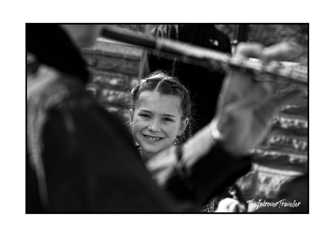 Young girl smiling at a street flutist performing in Central Park, New York