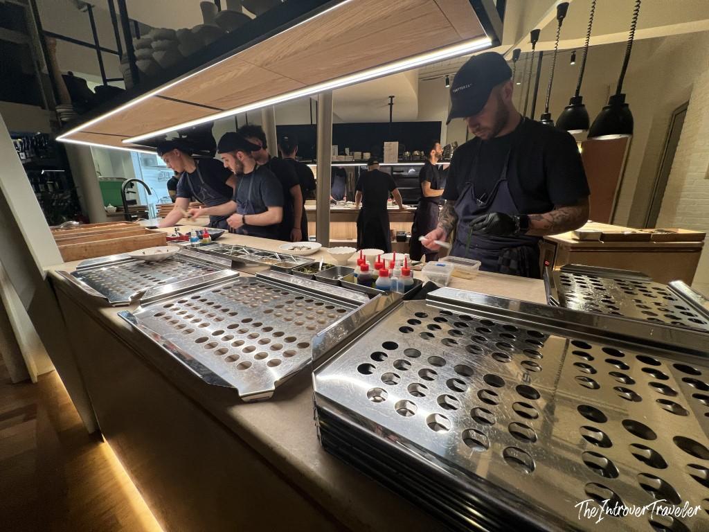 Chefs preparing dishes at an open kitchen counter in Trattoria Da Lucio, Rimini