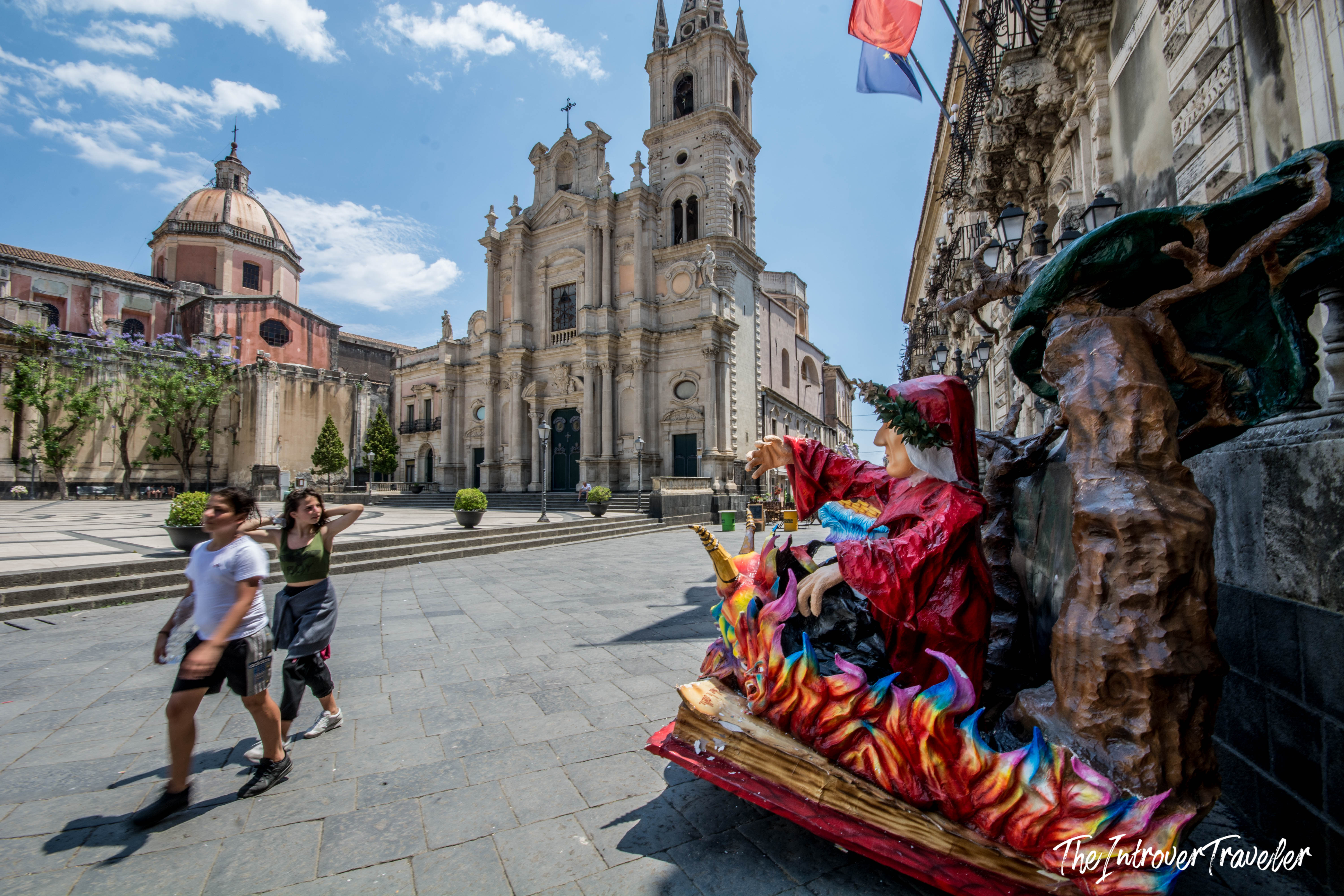 Colorful witch figure beside a baroque fountain in Piazza del Duomo, Acireale, Sicily