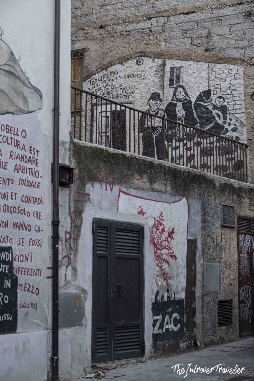 Political murals covering building walls in Orgosolo, Sardinia, with Italian text and figures