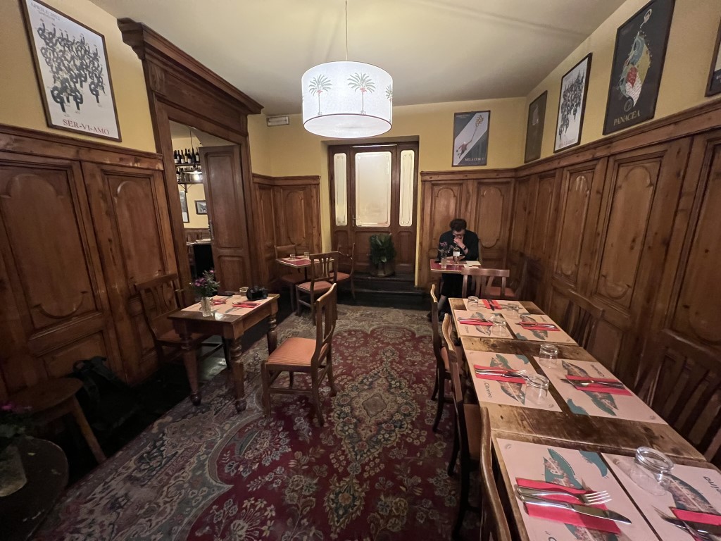 Cozy dining room at Trattoria Cibrèo Florence, with wood paneling, vintage posters, and set tables
