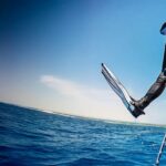Scuba diver in full gear stepping off a dive boat into open blue ocean waters