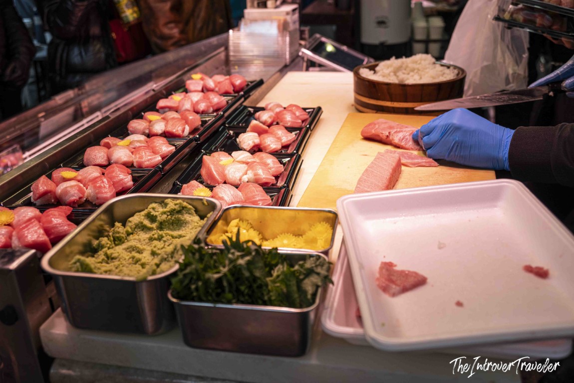 Fresh tuna nigiri sushi being prepared at a Tsukiji fish market stall, Tokyo, with wasabi and rice nearby