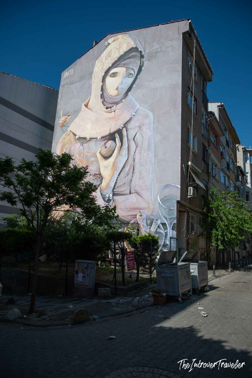 Large INTI mural on a building wall in Kadıköy, Istanbul, depicting a veiled figure holding a child
