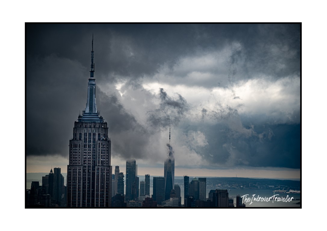 Empire State Building and One World Trade Center under dramatic storm clouds, viewed from Top of the Rock