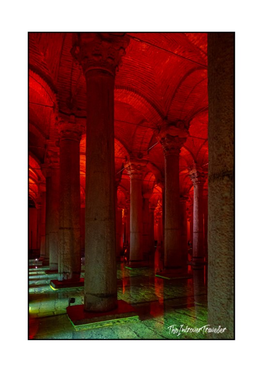 Basilica Cistern in Istanbul lit with dramatic red lighting, ancient columns reflected on wet floor