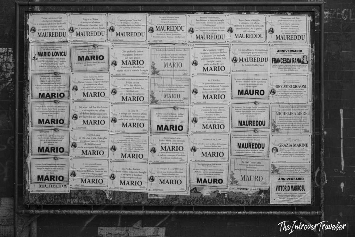 Black and white board of Italian death notices posted on a wall in Orgosolo, Sardinia