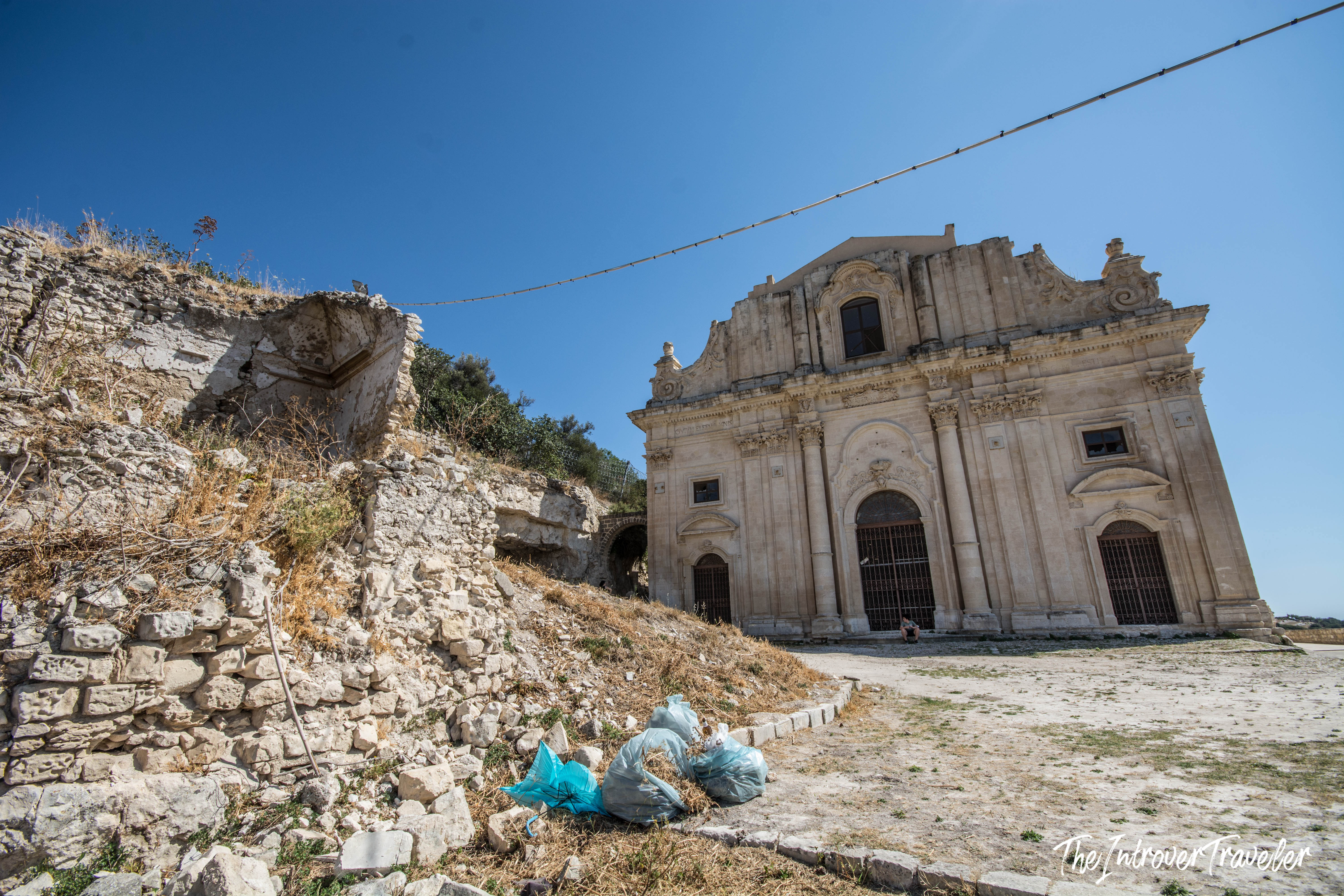 Baroque church facade in Val di Noto Sicily, beside crumbling stone ruins and rubble