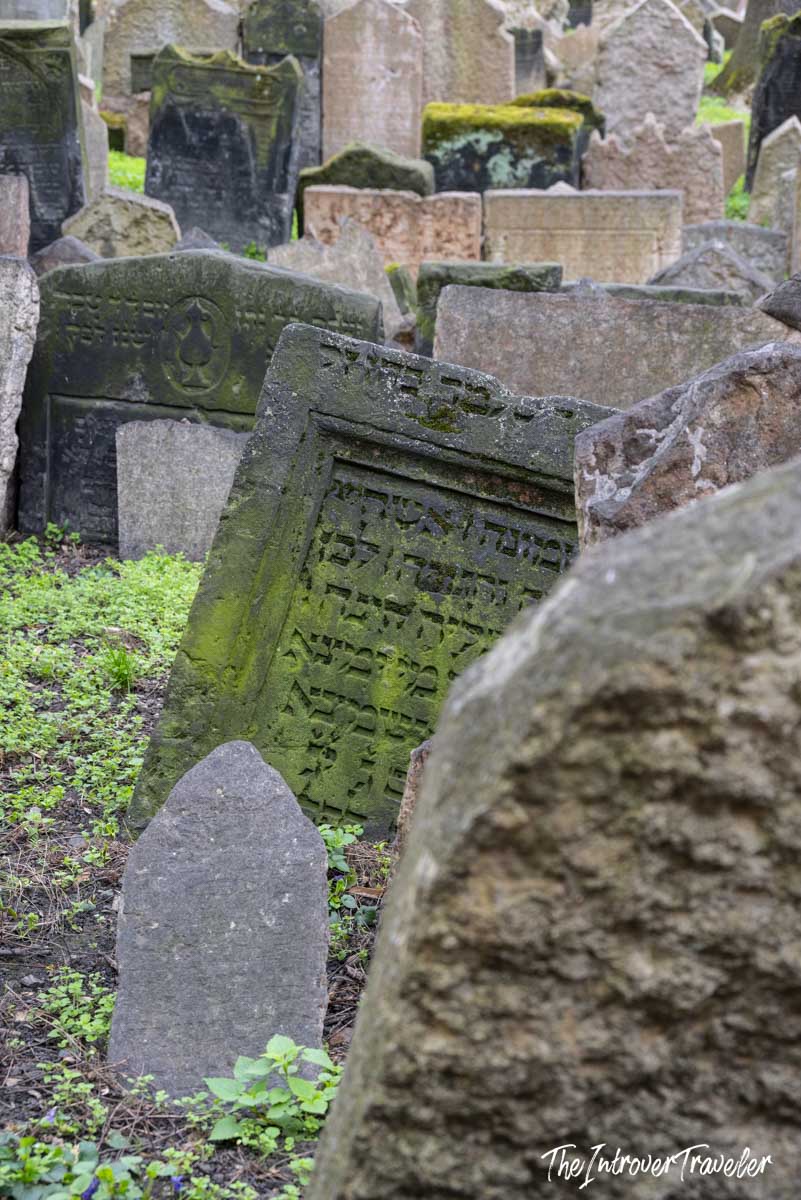 Densely packed Hebrew-inscribed gravestones leaning at angles in the Old Jewish Cemetery, Prague