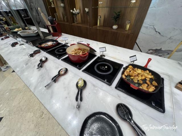 Warm food buffet station at CAC Lounge, Cairo Airport, with cast iron pans on induction hobs