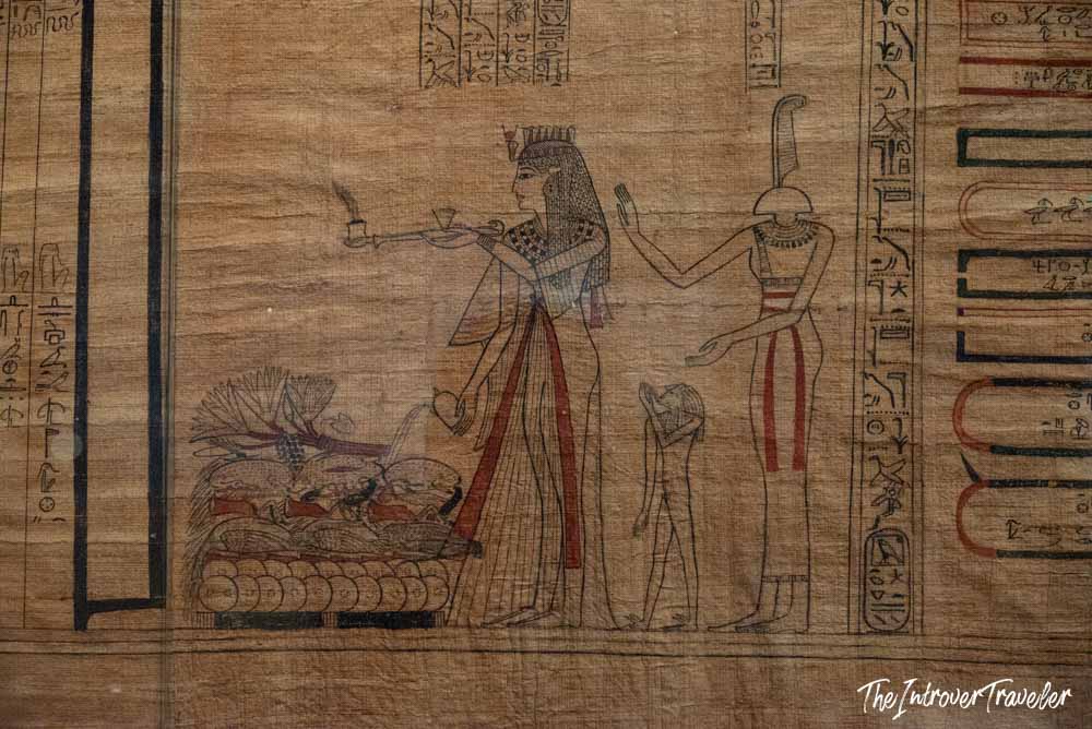 Ancient Egyptian papyrus scroll with hieroglyphs and deity figures on display at the Grand Egyptian Museum, Cairo