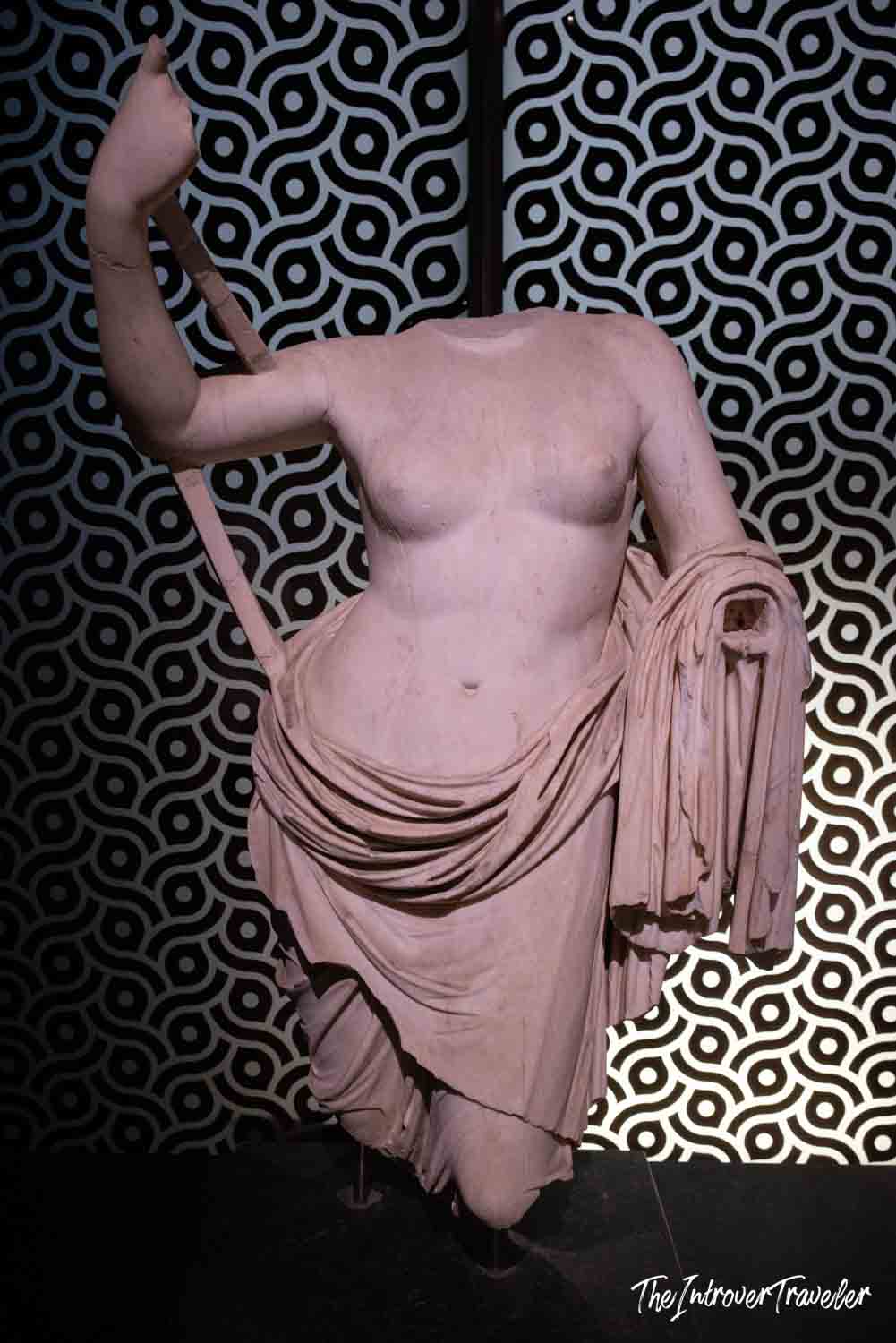 Headless ancient marble torso displayed against bold geometric patterned backdrop at Istanbul Archaeological Museum