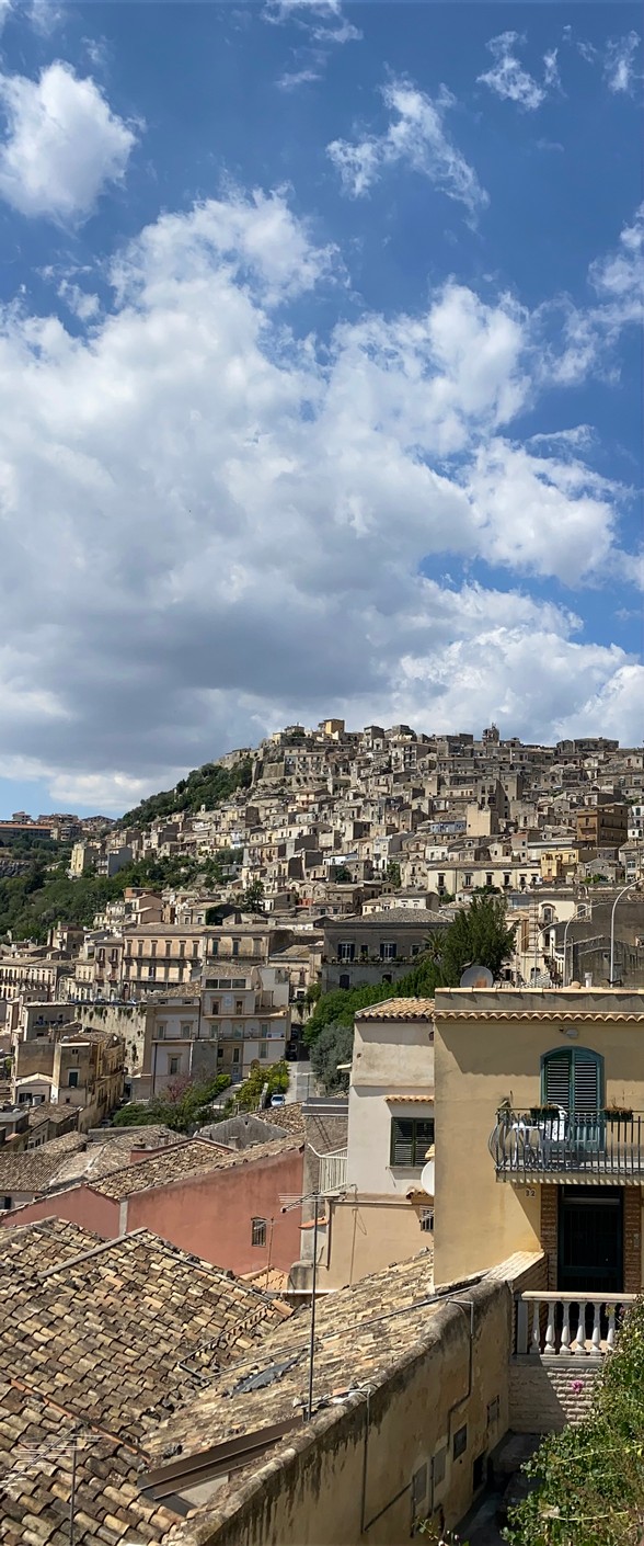 Rooftop view of Modica, a hilltop Baroque town in Val di Noto, Sicily, under a blue sky