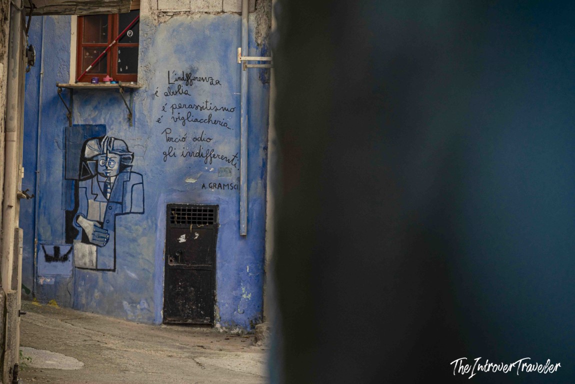 Street mural in Orgosolo featuring Antonio Gramsci portrait and Italian quote on indifference, Sardinia