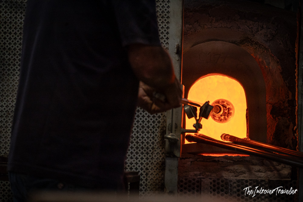 Murano glassblower heating molten glass in a glowing furnace on the island of Murano, Venice